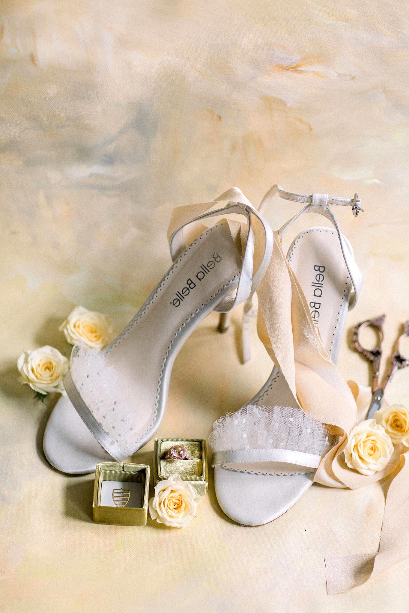 open toed bridal heels with pearl dot ruffled tulle straps and a pink engagement ring in a mustard velvet ring box